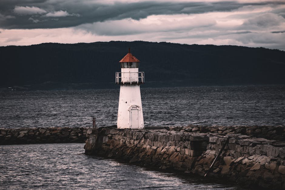Phare isolé sur la côte rocheuse norvégienne sous un ciel orageux et menaçant