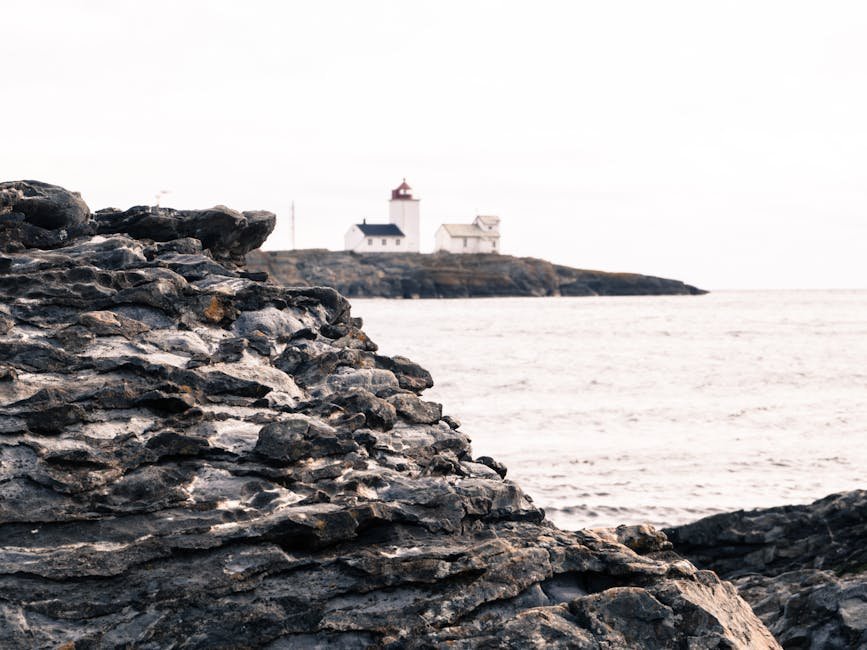 Phare blanc planté sur les rochers en Norvège avec la mer calme en arrière-plan